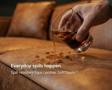 Drink being poured onto a brown M1 Faux Leather Sofa cushion, with liquid beading on the surface. Text reads “Everyday spills happen. Spill-resistant Faux Leather SoftTouch™.”