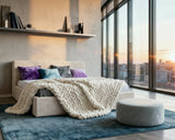 O2 Bed Cloud Frame, styled with colorful pillows and a chunky knit throw in a modern bedroom with floor-to-ceiling windows and city views.
