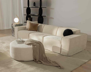 #Modular beige sofa from Rove Lab in a modern living room, featuring a marble side table with a spherical lamp, minimalistic shelving, and soft fabric decor on a round ottoman