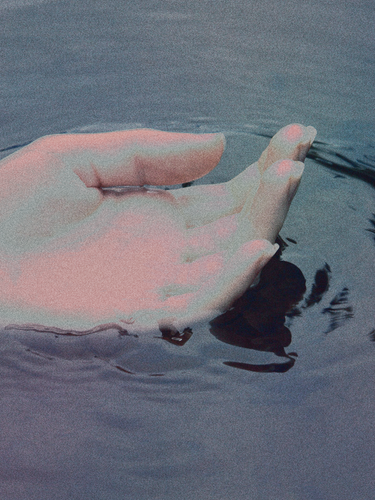 A serene image of a hand gently touching the water, creating ripples, symbolizing calmness and connection with nature