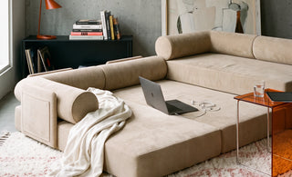 The S8 Sleeper Sofa Bed, fully expanded in a living room, with a cozy blanket and a laptop resting on top.