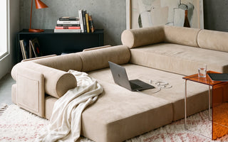 The S8 Sleeper Sofa Bed, fully expanded in a living room, with a cozy blanket and a laptop resting on top.