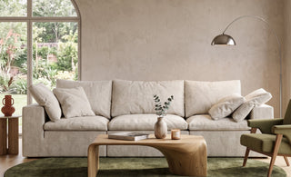 A modern living room featuring a plush modular sofa anchored by a large round rug on a wooden floor