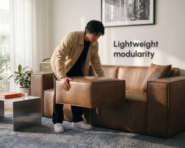 Man holding a lightweight ottoman and positioning it in his living room. 