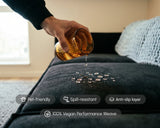 Spill-proof test on the M1 Sofa Sectional, with a hand pouring liquid from a glass onto the sofa.