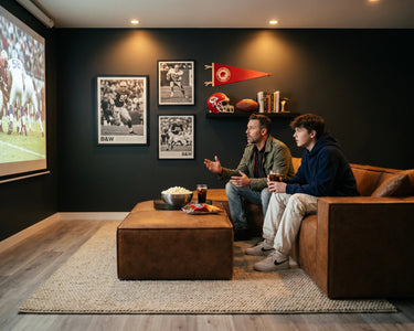 Two men playing video games with controllers in their hands, sitting on the M1 Sofa Sectional.