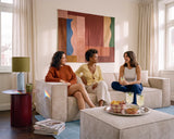 Three women chatting on a beige modular sofa, with drinks and snacks on a tray atop the matching ottoman.