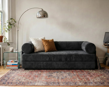 S8 Sleeper Sofa Bed in a living room, styled with two cushions, a rug, and a floor lamp beside it.