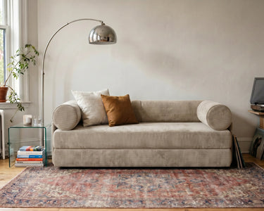 S8 Sleeper Sofa Bed in a living room, styled with two cushions, a rug, and a floor lamp beside it.